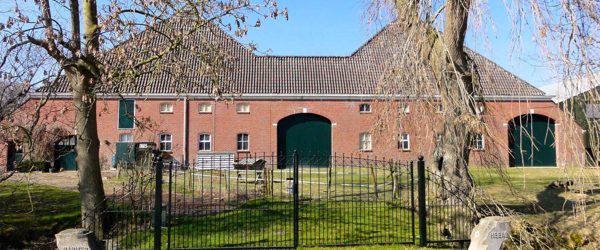 Große Scheune mit mehreren Toren hinter zwei Bäumen