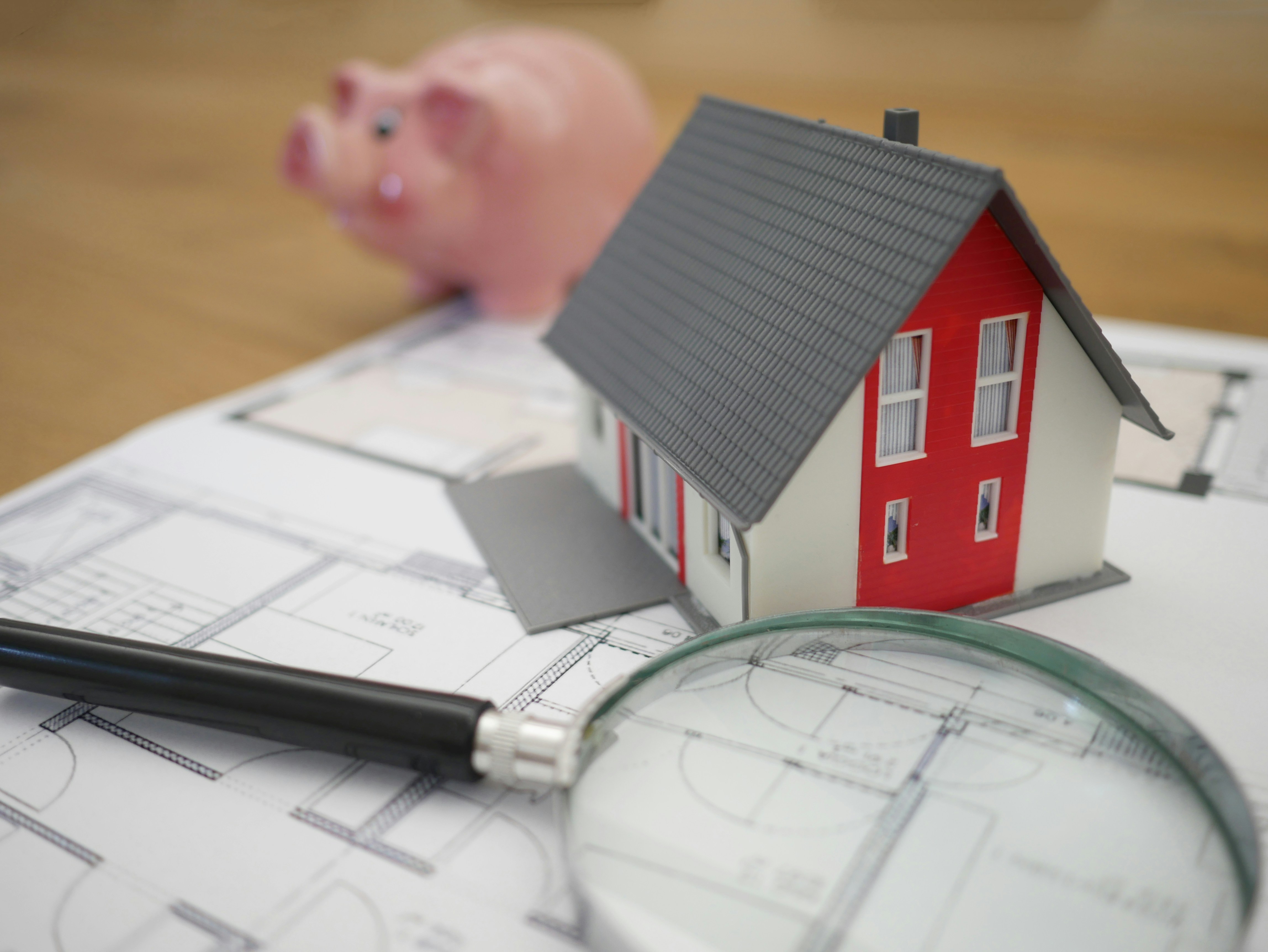 Modellhaus mit Plan, Lupe und Sparschwein